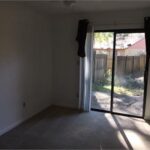 Empty room with sliding glass door to backyard.