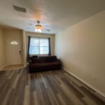 Empty living room with a couch and wood floor.