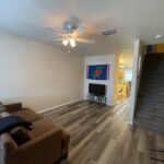 Living room with couch, TV, and stairs.