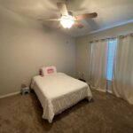 Bedroom with bed, fan, and curtains.