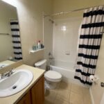 White bathroom with black and white shower curtain.