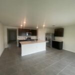 Empty kitchen with white cabinets and grey tile.