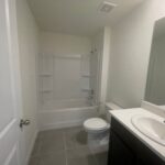 White bathroom with bathtub, toilet, and sink.