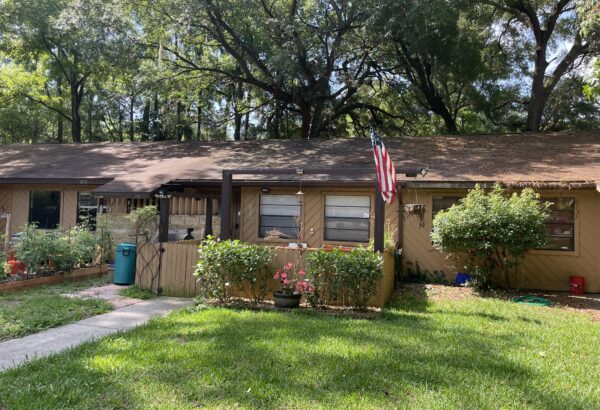 American flag flies outside tan house.