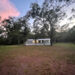 Single-story house in a wooded area.