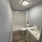 White bathroom with shower, toilet, and sink.