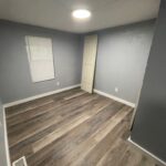 Empty room with wood flooring and a door.