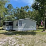 Grey mobile home with an American flag.