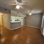 Empty living room with wood floors and ceiling fans.