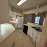 White kitchen with stainless steel sink and tile floor.