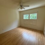 Empty bedroom with wood floors and windows.