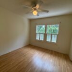 Empty bedroom with wood floor and fan.