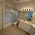 White bathroom with shower, toilet, and sink.