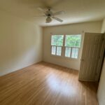 Empty bedroom with hardwood floors and windows.