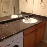 Bathroom with sink, cabinets, and washer.