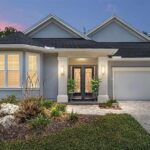 Gray house with black double doors and a garage.