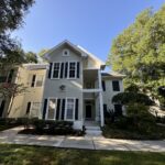 White house with black shutters and green trees.