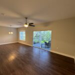 Empty living room with wood floor and patio view.
