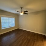 Empty bedroom with ceiling fan and wood floor.