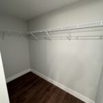Empty closet with white shelves and dark floor.