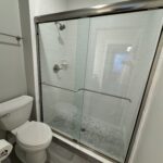White tiled bathroom with glass shower stall.