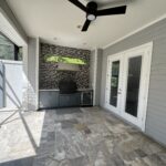 Outdoor kitchen with tile floor and ceiling fan.