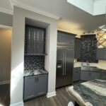 Modern kitchen with stainless steel fridge and gray cabinets.