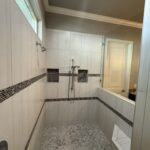 Modern shower with tiled walls and bench.