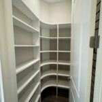 White corner pantry with shelves and door.