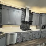 Modern kitchen with gray cabinets and stainless steel appliances.