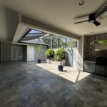 Tiled patio with ceiling fan and plants.