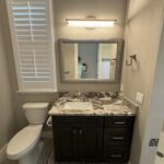 Modern bathroom with granite countertop and shower.