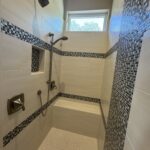 Modern shower with tiled walls and seat.
