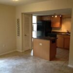 Empty living room with kitchen in the background.