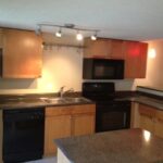 Modern kitchen with black appliances and wood cabinets.