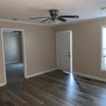 Empty living room with wood floors, door and window.