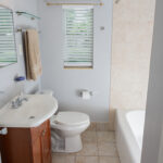 White bathroom with toilet, sink, and tub.