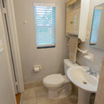 White bathroom with tiled floor and a window.