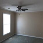 Empty bedroom with ceiling fan and window.