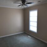 Empty bedroom with a ceiling fan and window.