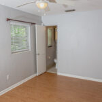 Empty bedroom with wood floors and bathroom door.