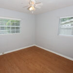 Empty bedroom with wood floor and ceiling fan.