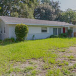 White suburban house with green lawn.