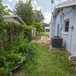 Side of house with AC unit and flowers.