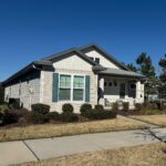 Beige house with gray roof and shutters.