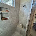 Modern gray tiled shower with built-in shelves.