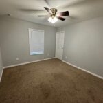 Empty bedroom with carpet and ceiling fan.