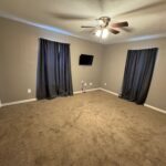 Empty carpeted bedroom with ceiling fan.