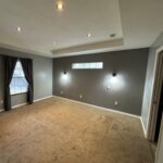 Empty carpeted room with gray walls.