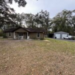 House and garage in wooded area.